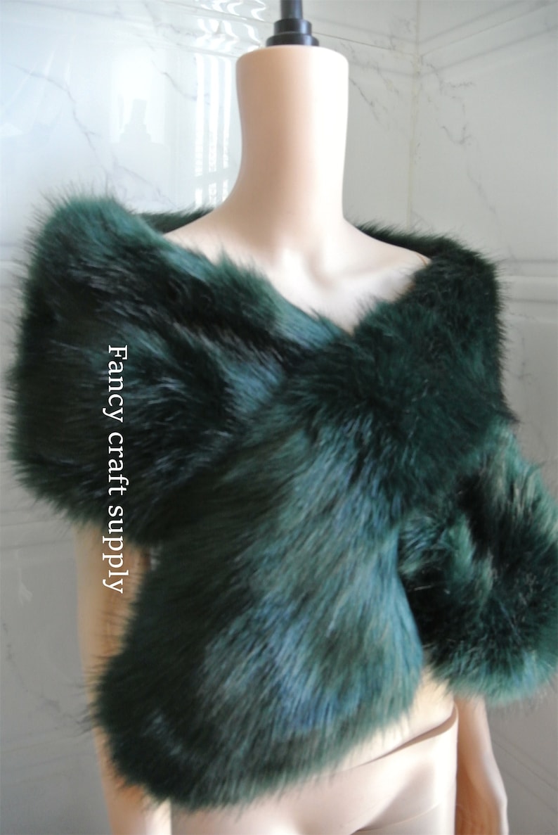 May include: A dark green faux fur shawl. The shawl is draped over a white mannequin. The text "Fancy craft supply" is visible on the shawl.
