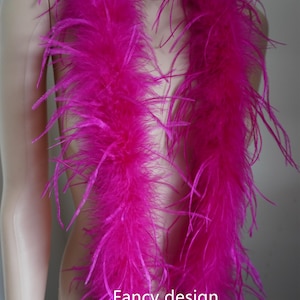 May include: A vibrant magenta feather boa draped over a mannequin. The boa is thick and fluffy, with long, delicate feathers. The text "Fancy design" is visible on the image.