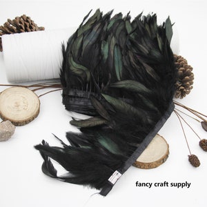 May include: Black feather trim with a green iridescent sheen. The trim is approximately 10 inches wide and is attached to a black ribbon.