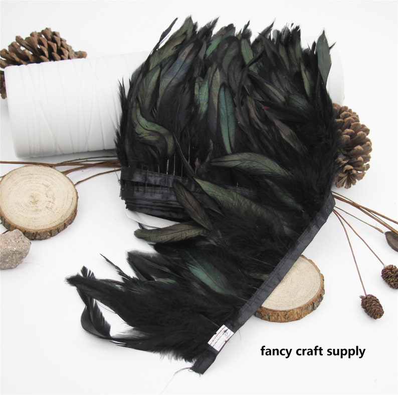 May include: Black feather trim with a green iridescent sheen. The trim is approximately 10 inches wide and is attached to a black ribbon.
