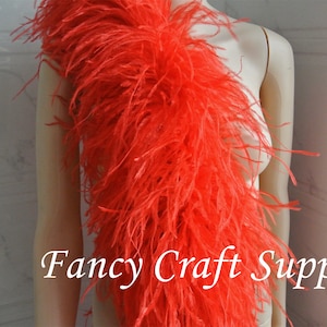 May include: A long, bright orange ostrich feather boa. The boa is draped over a white mannequin. The text "Fancy Craft Supply" is visible in the bottom right corner of the image.
