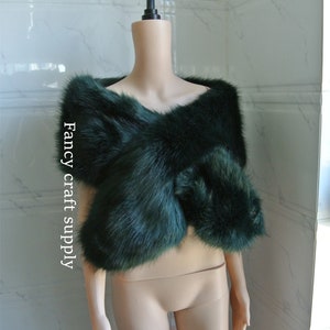 May include: A dark green faux fur shawl draped over a mannequin. The shawl is made of soft, fluffy fur and has a simple, elegant design.