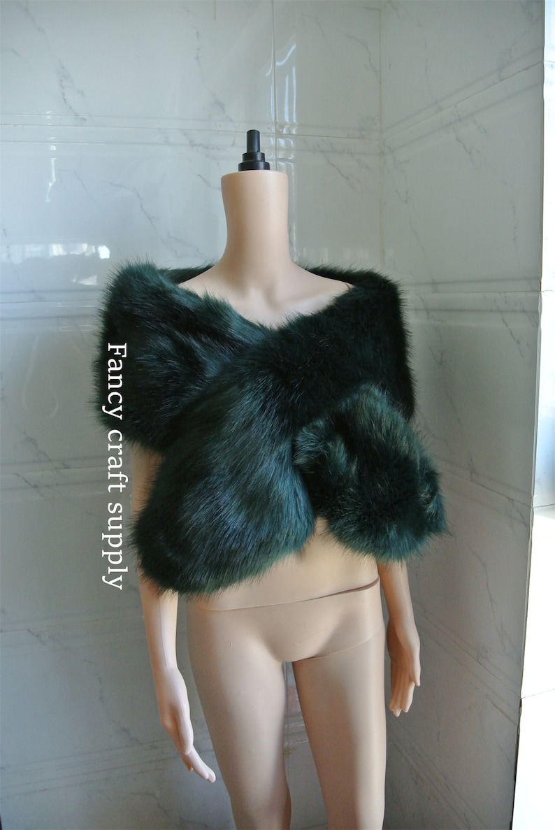 May include: A dark green faux fur shawl draped over a mannequin. The shawl is made of soft, fluffy fur and has a simple, elegant design.