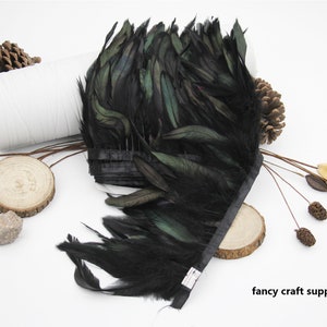 May include: Black feather trim with a green iridescent sheen. The feathers are attached to a black ribbon. The trim is approximately 10 inches long.