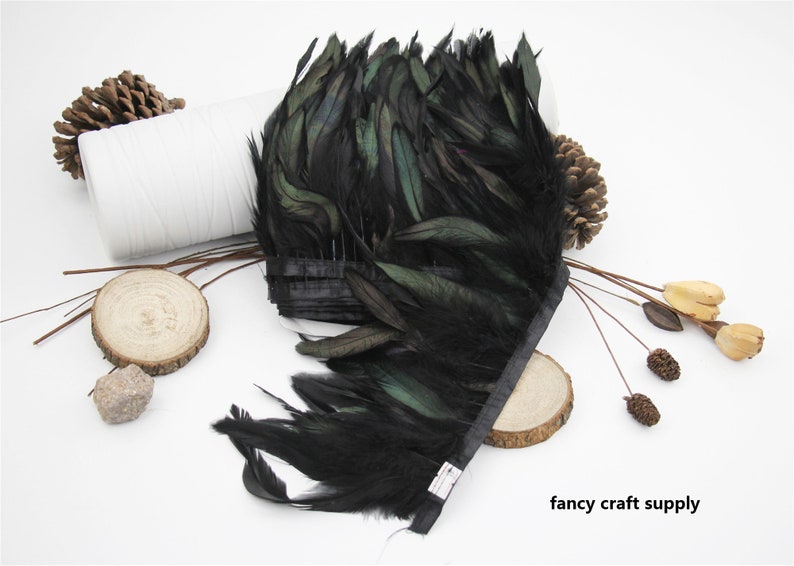 May include: Black feather trim with a green iridescent sheen. The feathers are attached to a black ribbon. The trim is approximately 10 inches long.