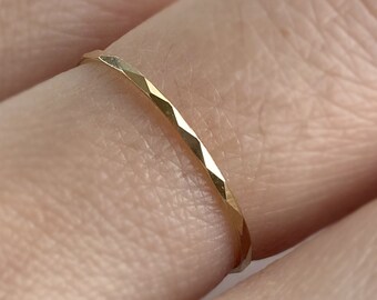 May include: A thin gold band ring with a hammered texture.