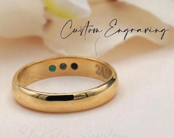 May include: A gold wedding band with a custom engraving and three small gemstones. The engraving reads "Custom Engraving".
