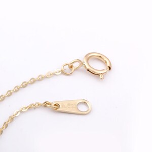 Op de afbeelding: Een gouden ketting met een karabijn sluiting en een veer sluiting. De ketting is gemaakt van kleine, ronde schakels.