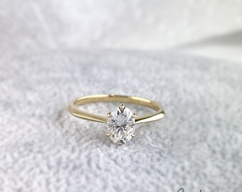 May include: A gold band ring with a single oval-shaped diamond.