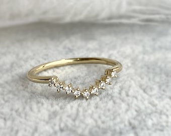 May include: A gold band ring with a row of small diamonds set in a curved shape.