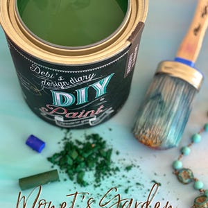 May include: A can of green paint with the text "Debi's design diary DIY Paint" on the label. The paint is surrounded by green paint chips and a paintbrush. The text "Monet's Garden Beautiful Masterpiece" is at the bottom of the image.