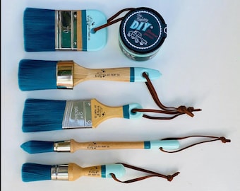 May include: Set of five paint brushes with teal bristles and wooden handles. The brushes have blue and white accents and brown leather straps. A small teal jar of paint is included with the text "DIY" on the label.