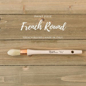 May include: A close-up of a French Round paint brush with a wooden handle and a copper ferrule. The brush is made in Italy and is labeled "Paint Pixie".