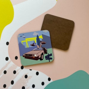 Könnte beinhalten: Ein quadratischer Untersetzer mit einer bunten Illustration eines futuristischen Autos, das eine Straße entlangfährt, mit einem Schild, auf dem "CYRUS AVE BOTANIC GARDENS" steht.