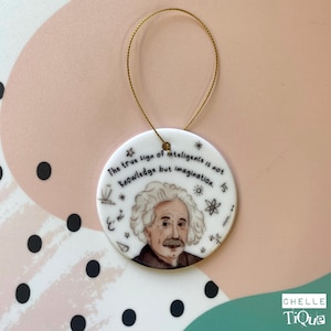 Puede incluir: Adorno redondo de cerámica blanca con un retrato de Albert Einstein y la cita: "El verdadero signo de la inteligencia no es el conocimiento sino la imaginación". Tiene una cuerda dorada para colgar y símbolos científicos.