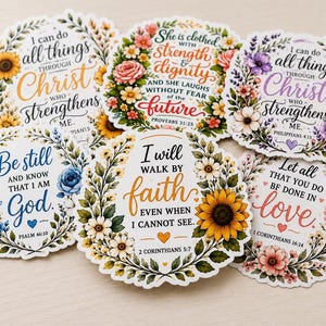 May include: A collection of five circular stickers featuring floral wreaths and religious text. The designs include phrases like I can do all things through Christ, She is clothed with strength and dignity, Be still and know that I am God, I will walk by faith, and Let all that you do be done in love, surrounded by colorful illustrations of sunflowers, roses, and daisies.