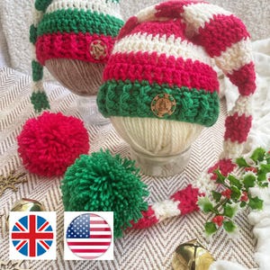 May include: Handmade crochet elf hats in festive red, green, and white stripes, with wooden button embellishments. The hats are displayed on a white yarn base, with red and green pom-poms. A sprig of holly and a gold bell are also visible.
