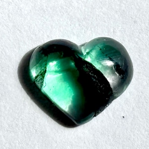 以下が含まれることがあります： 濃い緑と黒の虹色の光沢を持つハート型の緑色の宝石