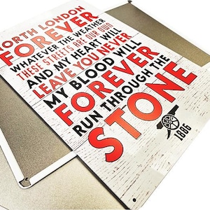 Puede incluir: Un letrero de metal blanco con texto negro y rojo. El letrero dice "North London Forever" y "My blood will forever run through the stone". El letrero también incluye el año "1886".