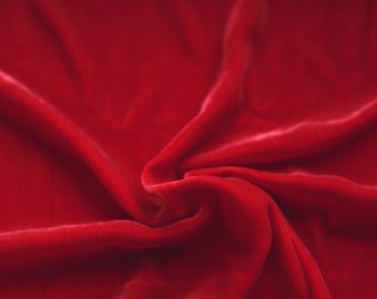 Może przedstawiać: Zbliżenie na głęboki czerwony materiał welurowy z miękkimi fałdami i zmarszczkami. Materiał ma luksusowy i elegancki wygląd.
