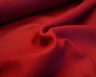 May include: A close-up of a deep red fabric with a soft, fuzzy texture. The fabric is folded and draped, showing its smooth, even surface.