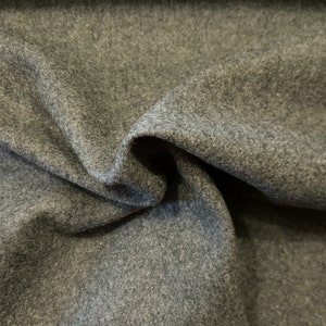 May include: Close-up of a grey, textured fabric with a subtle sheen. The fabric is folded and draped, showcasing its soft and drapey texture.