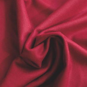May include: Close-up of a deep red fabric with a soft, smooth texture. The fabric is folded and draped, creating a luxurious and elegant look.