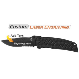May include: Black folding knife with a serrated blade and textured handle. The blade has the text "Engraving Here" and an arrow pointing to it. The knife is designed for custom laser engraving. The text "Custom Laser Engraving" is above the knife.