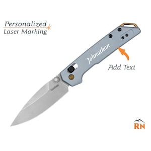 May include: A light gray folding knife with a silver blade. The knife has the name "Johnathan" engraved on the handle. The text "Add Text" and "Personalized Laser Marking" are also visible.