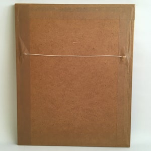 May include: The back of a brown picture frame with a white string attached to the top for hanging.