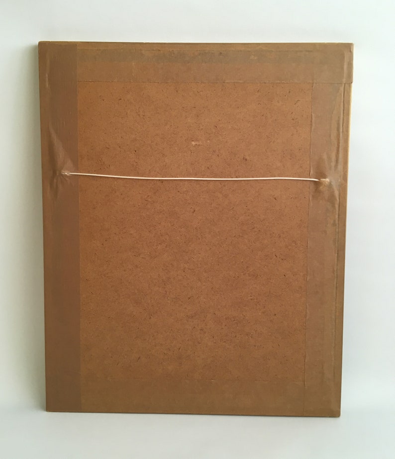May include: The back of a brown picture frame with a white string attached to the top for hanging.