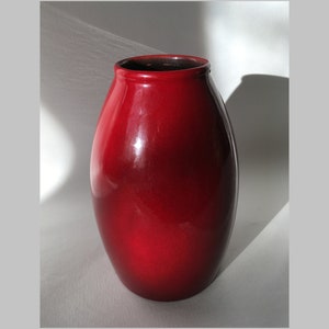 Peut inclure: Un vase en céramique rouge brillant de forme arrondie et bulbeuse.