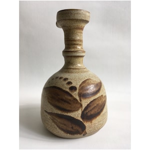 May include: A brown and beige ceramic vase with a wide base and a narrow neck. The vase has a brown leaf design.