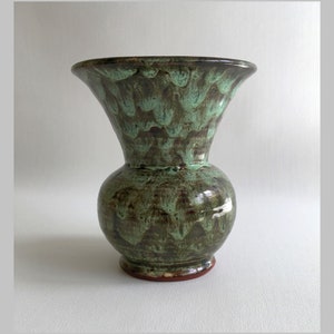 May include: A green and brown ceramic vase with a flared opening and a rounded body. The vase has a mottled glaze with a green and brown pattern.