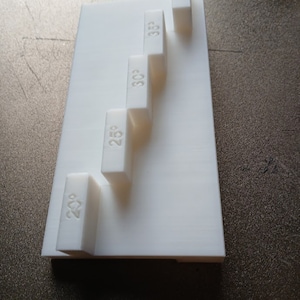May include: A set of five white plastic blocks with numbers printed on them. The numbers are 20, 25, 30, 35, and 50.