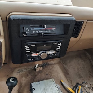 May include: A black car dashboard with a radio, climate control panel, and a gear shifter. The radio has a Bluetooth logo and the text "Beat". The climate control panel has the text "Cool", "A/C", "Heat", and "Vent Floor Floor Defrost". The gear shifter has the text "2H 4H N 4L".