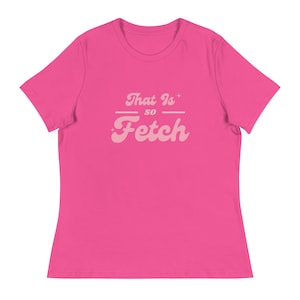 May include: A vibrant pink t-shirt featuring the text "That Is so Fetch" in a light pink, vintage font. The phrase is centrally positioned, with star motifs flanking the word "Is". A casual, everyday garment.