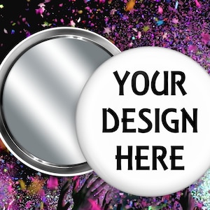 May include: Two white round buttons with a silver backing. One button displays the text "YOUR DESIGN HERE" in black. The background is a colorful confetti design with hands reaching up.
