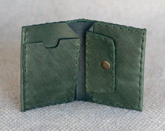 May include: A green leather wallet with a stitched edge and a button closure. The wallet has multiple compartments for cards and cash.
