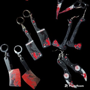 May include: A set of 10 black and red earrings featuring various bloody weapon shapes, including knives, axes, and a cleaver.