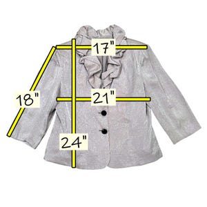 K&ouml;nnte beinhalten: Silberfarbener Blazer mit R&uuml;schenkragen und drei schwarzen Kn&ouml;pfen. Die Jacke misst 43 cm &uuml;ber den Schultern, 53 cm &uuml;ber der Brust und 61 cm in der L&auml;nge, mit 46 cm &Auml;rmeln.
