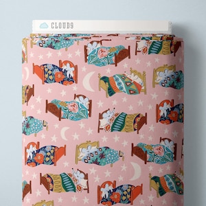 May include: A roll of fabric with a repeating pattern of beds, mice, stars, and moons on a pink background. The beds have colorful floral and geometric bedding. The text "CLOUD9" is visible on the top edge of the fabric.