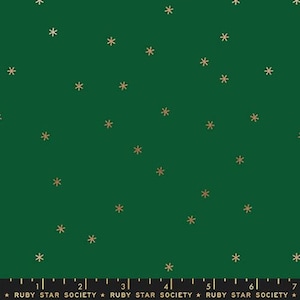 May include: A green fabric with a repeating pattern of gold snowflakes. The fabric is marked with a ruler in inches and the text "RUBY STAR SOCIETY".