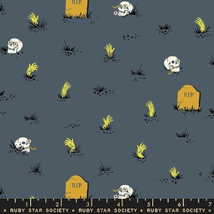 May include: A blue fabric with a repeating pattern of yellow skeletal hands, skulls, and tombstones with the word "RIP" on them. The fabric has a black ruler with white markings at the bottom.