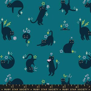 May include: A teal fabric featuring a repeating pattern of dark navy cats in various poses, including stretching, sitting, and holding a cup. The design includes yellow lightning bolts, white stars, and small hearts. A ruler is visible at the bottom edge.