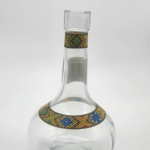 May include: A white ceramic mug with a black handle and the text "But First, Coffee" in a bold, black font. The mug is set against a blurred background, suggesting a cozy setting. The mug appears to be approximately 4 inches tall.