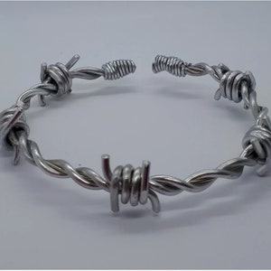May include: A silver barbed wire bracelet. The bracelet is made of twisted wire with sharp points.