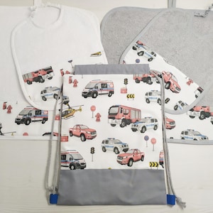 May include: A set of four white and grey fabric items featuring a fire engine, police car and ambulance theme. The set includes a bib, two tea towels and a drawstring bag.