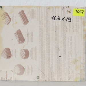 May include: A close-up of a white paper with a description of different types of chocolates. The paper is labeled "Assortment of Chocolates" and includes the text "16.5 x 19". A yellow sticky note with the number "1067" is in the top right corner.
