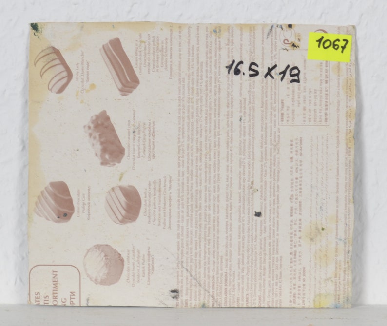 May include: A close-up of a white paper with a description of different types of chocolates. The paper is labeled "Assortment of Chocolates" and includes the text "16.5 x 19". A yellow sticky note with the number "1067" is in the top right corner.